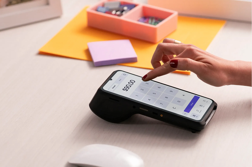 Pharmacy staff holding Helcim mobile payment terminal