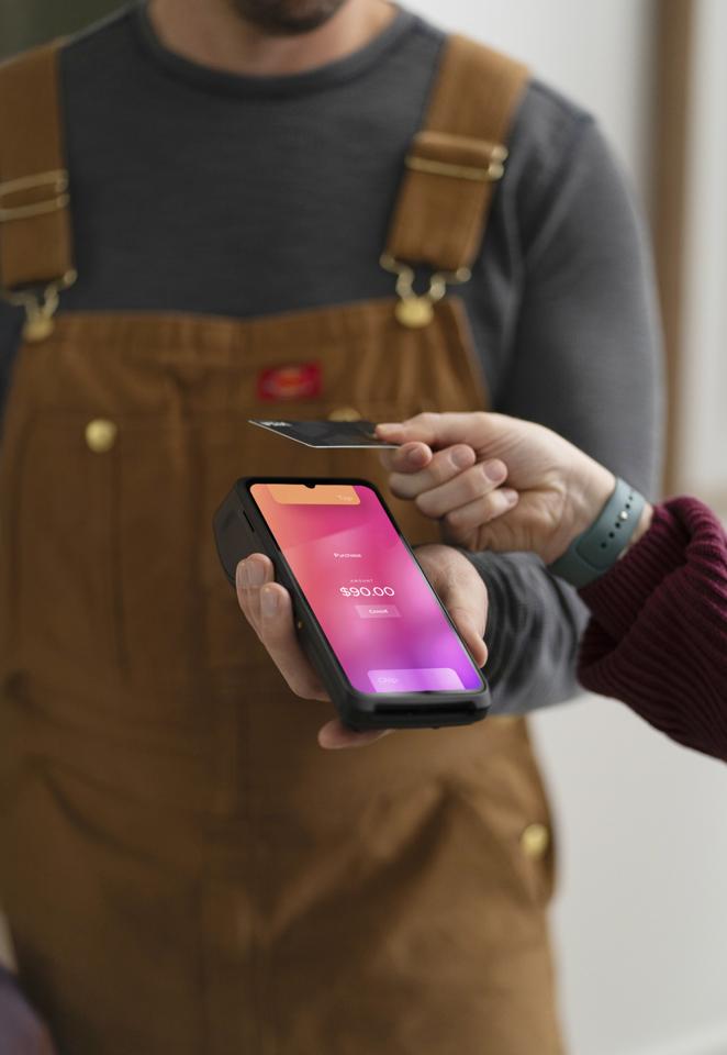 Merchant holding Helcim Smart Terminal while customer inserts card