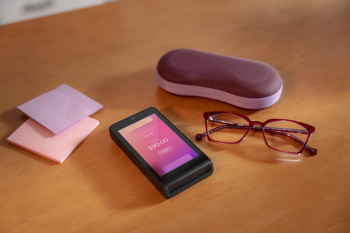 Helcim Smart Terminal on office desk with glasses and sticky notes