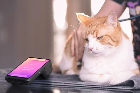 Smiling vet clinic receptionist holding Helcim mobile payment terminal