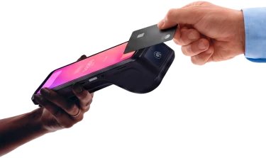 Two hands exchanging a card payment on a Helcim card reader