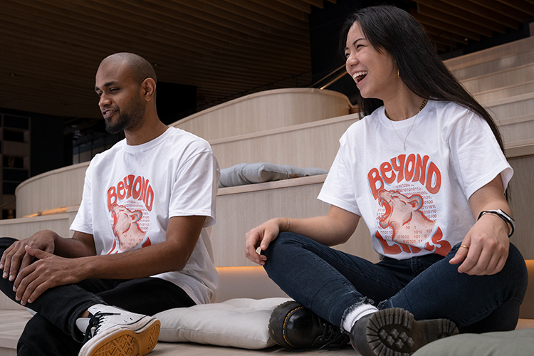 Helcim Employees Danny Jose and Gina Gong (T-shirt Designer) pictured left to right sitting wearing new Beyond Limit Series T-shirts for IWD