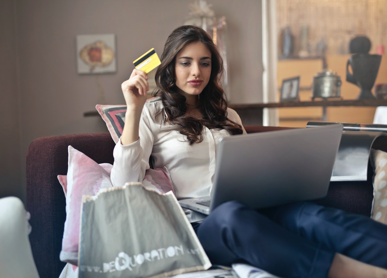 person holding a credit card looking at a laptop to make a transaction