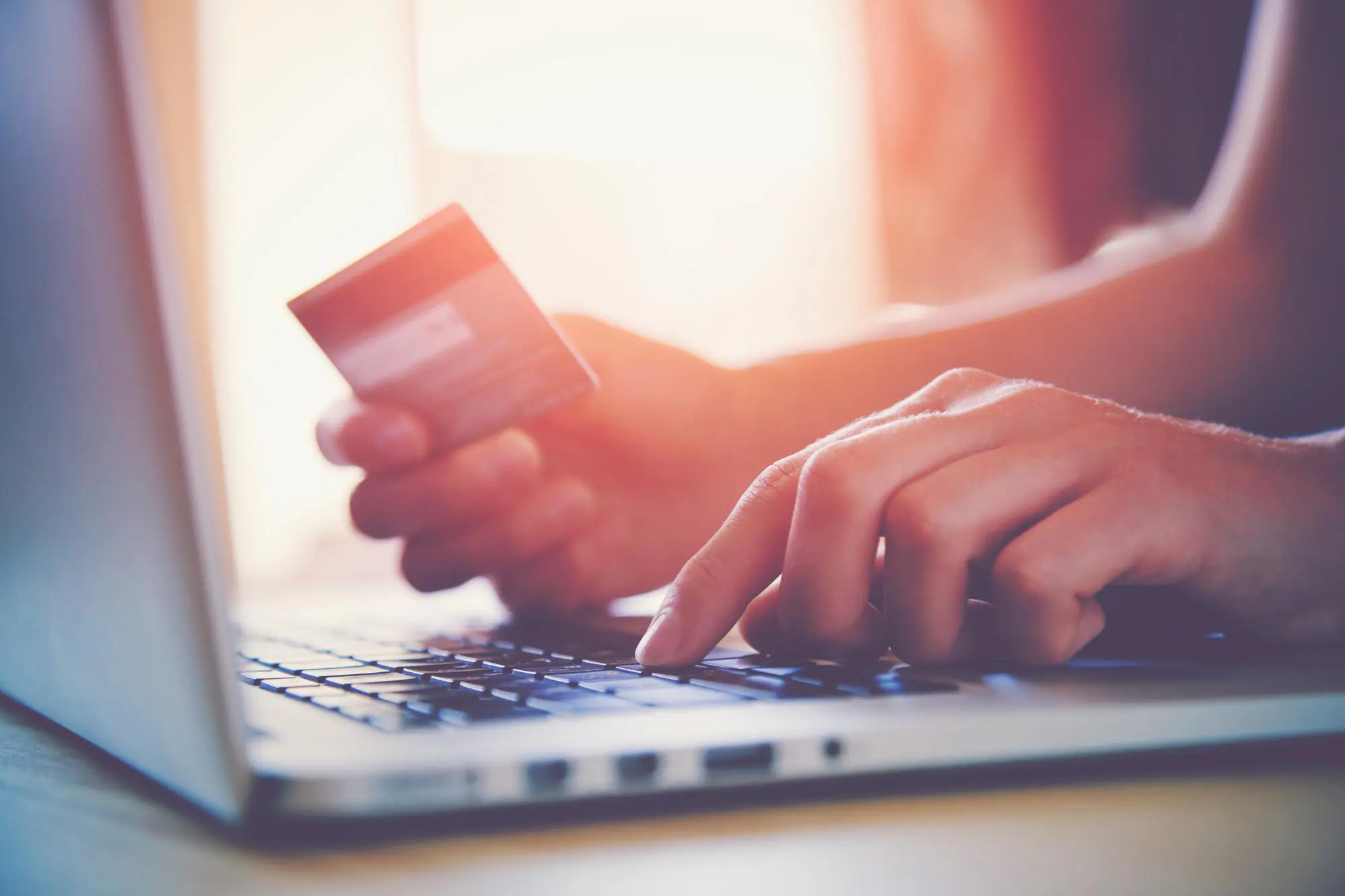 A person making a payment online with their credit card and their laptop