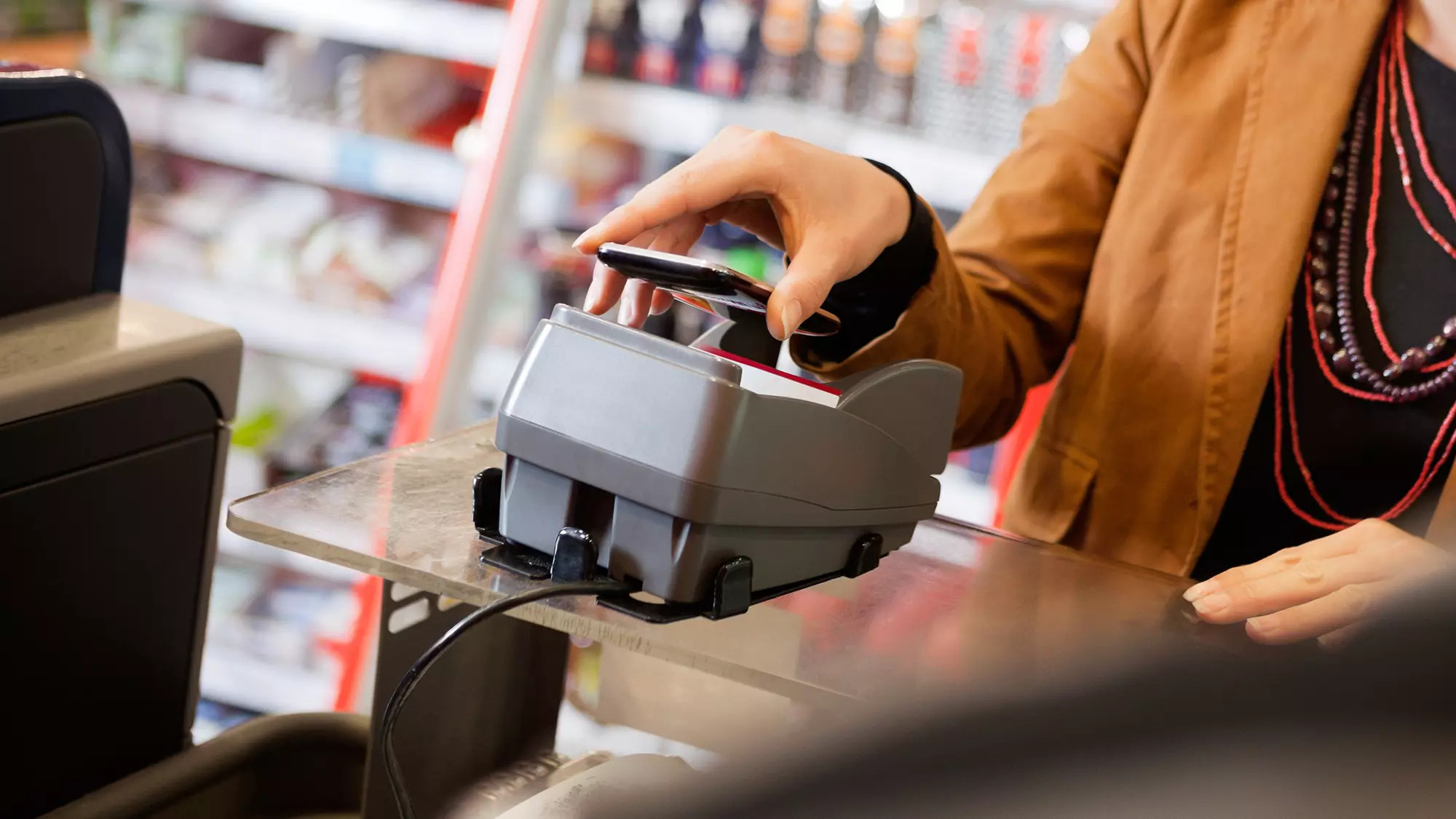 a person making a contactless payment with a cellphone to a card reader