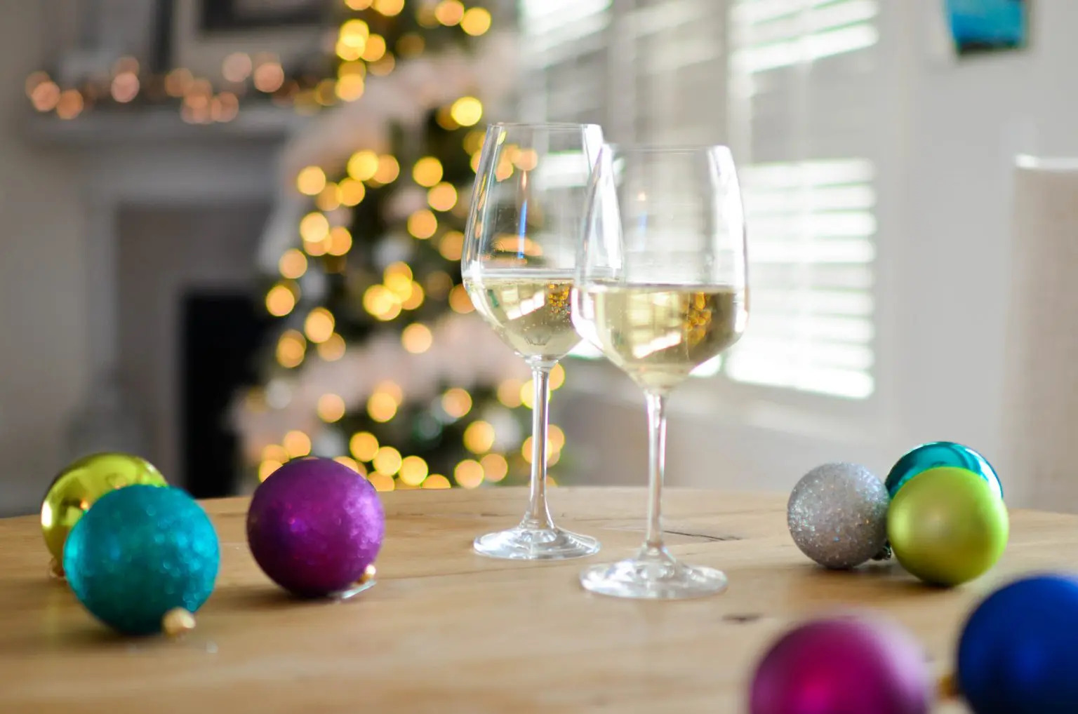 Two glasses of white wine on a table in front of a Christmas Tree