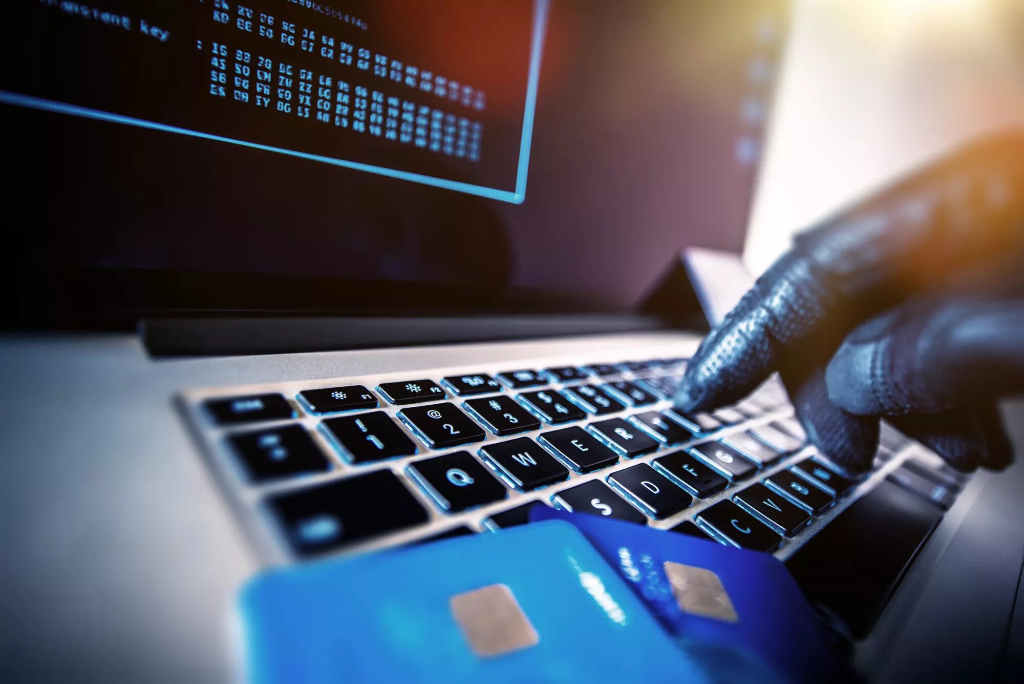 gloved hand in black typing on keyboard alluding on fraud