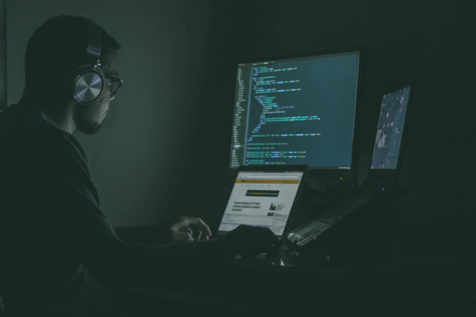 man sitting in front of many computer screens looking at code for web security