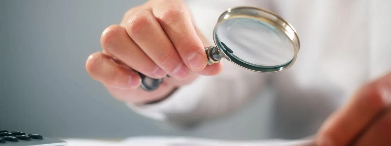 person looking at fees charged with a magnifying glass