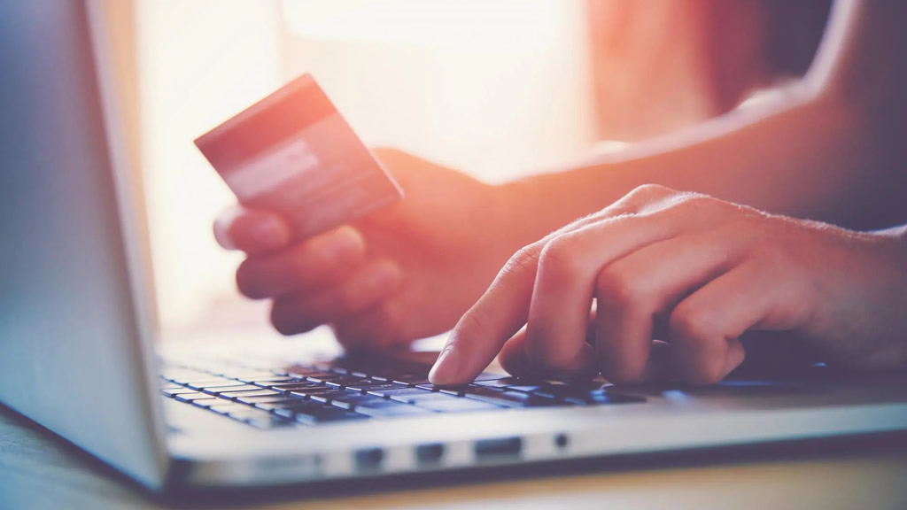 A person making a payment online with their credit card and their laptop
