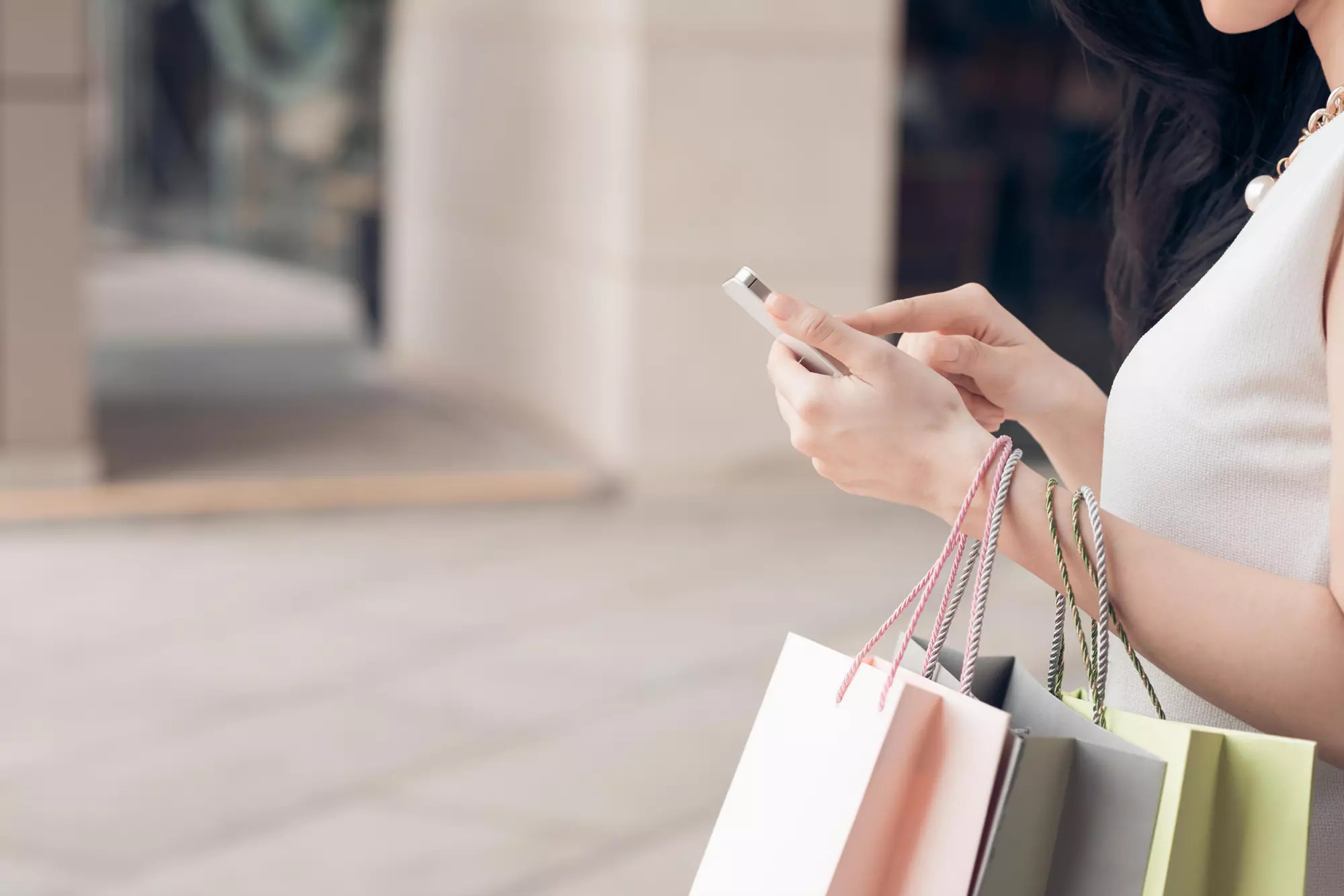 a person holding a few shopping bags while shopping on a phone