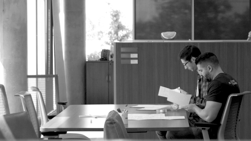 Nic and Daniel working reading at a table in the Helcim office