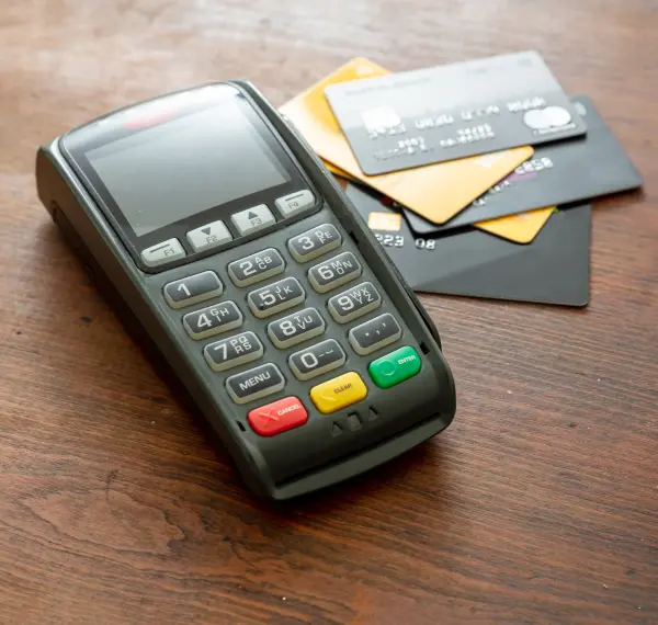 an image of a traditional pos terminal next to credit cards
