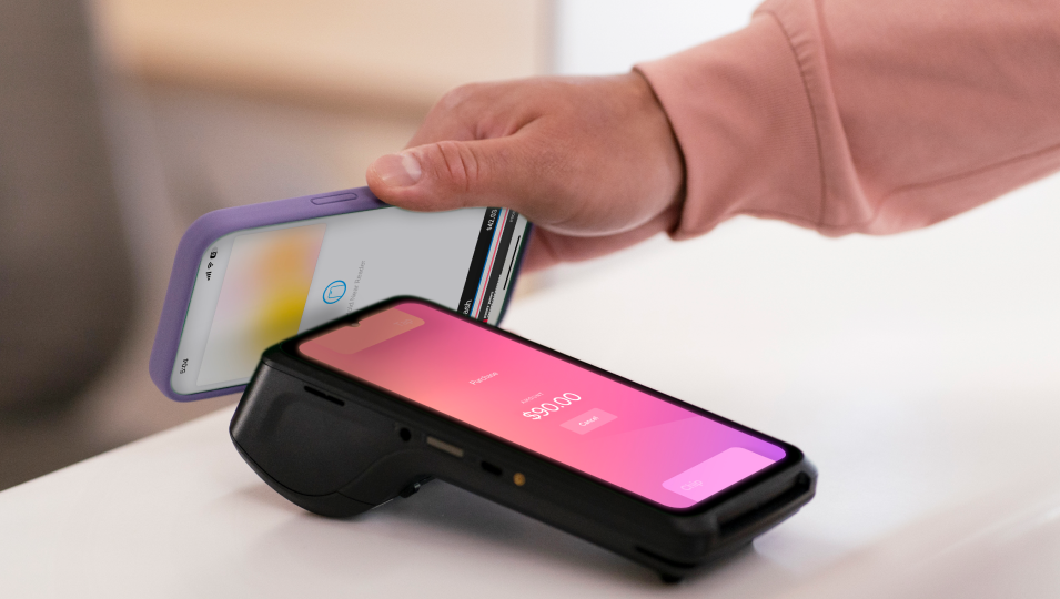 A person making a contactless payment to purchase flowers with a payment card on a Helcim credit card machine
