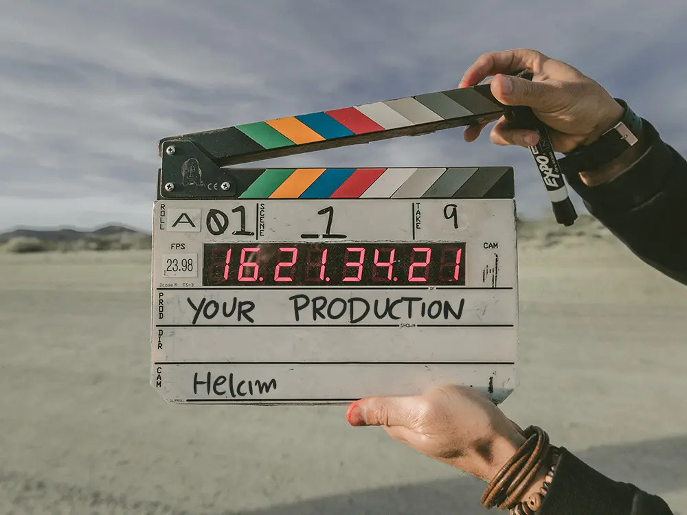 A clapperboard with 'your production' and 'Helcim' written on it