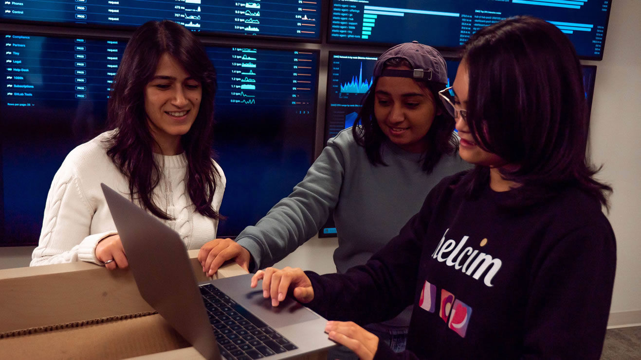 From left to right Niloofar, Amnah, and Zoe at Helcim looking at a laptop